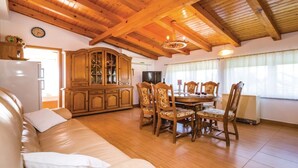 Uma sala de estar aconchegante com teto de madeira, um sofá, uma mesa de jantar com cadeiras e um armário.