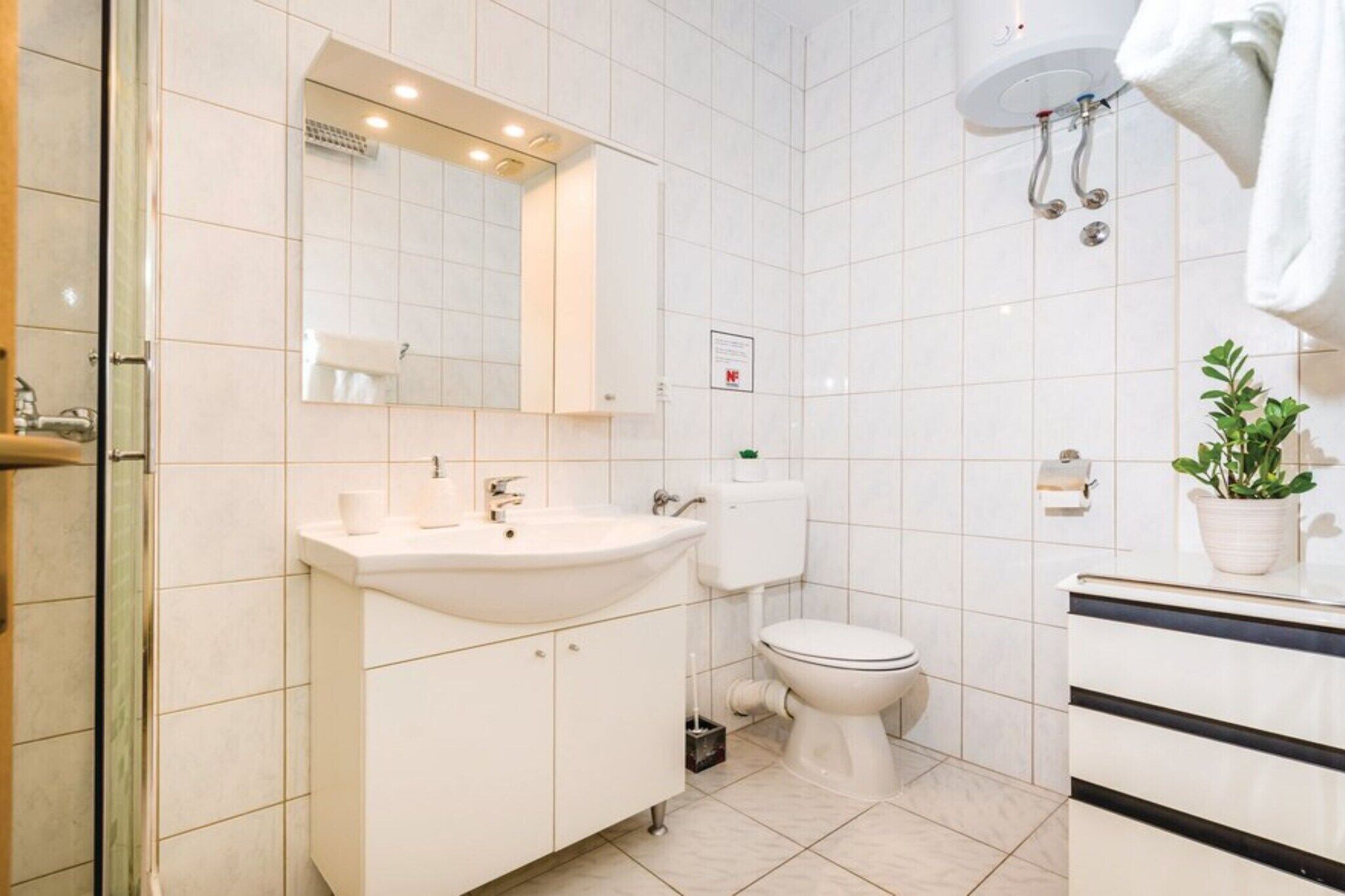 Ein modernes Badezimmer mit Waschbecken, Toilette und Spiegel in Weiß.