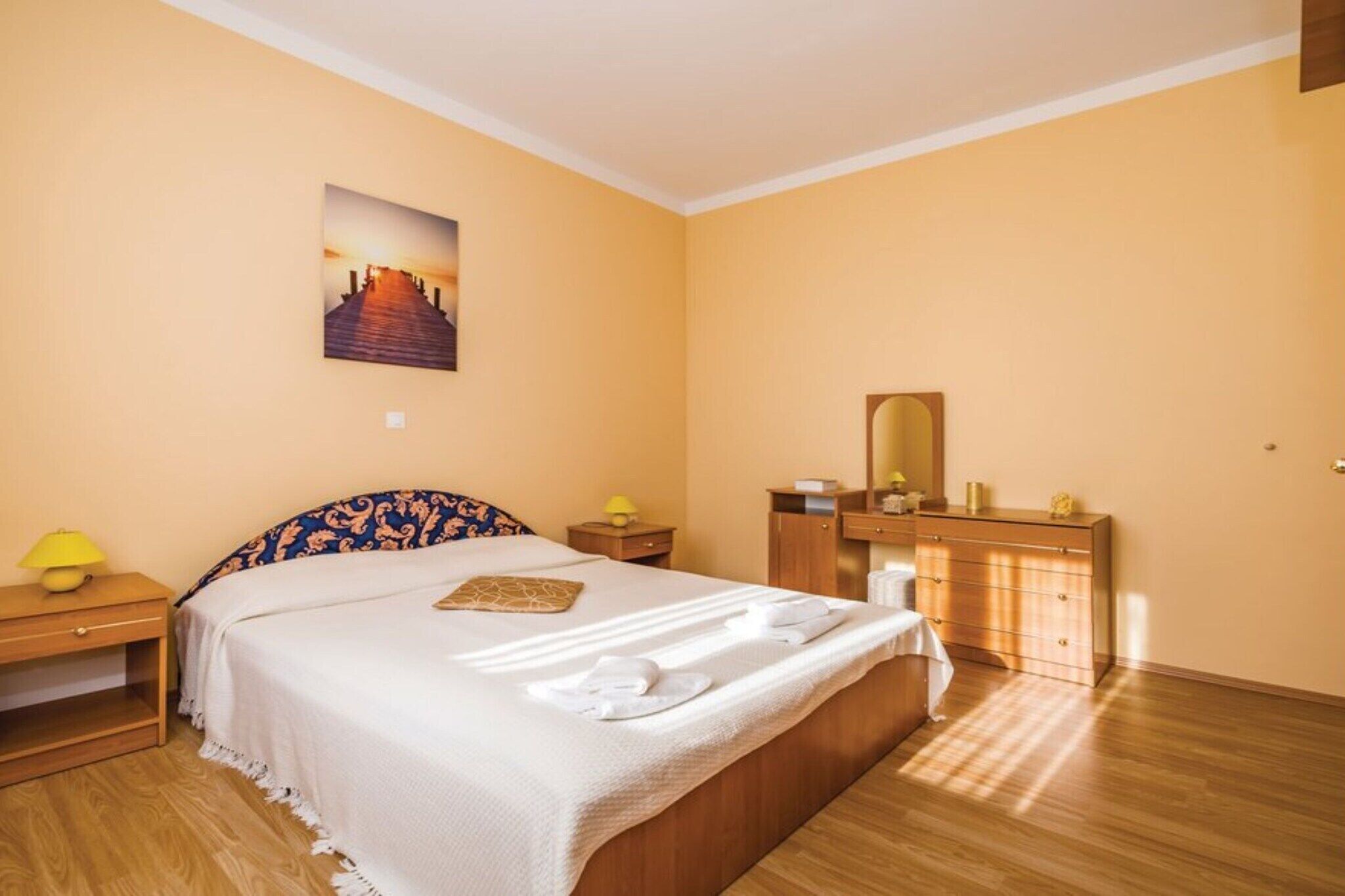 Une chambre d’hôtel avec un lit, une table de chevet, une commode et un miroir.