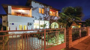 Uma casa de dois andares com varanda, muro de pedra e portão.