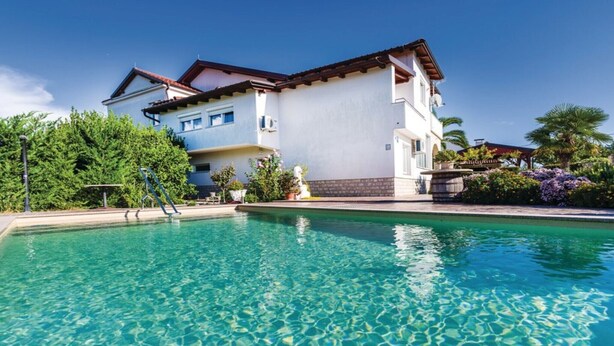 Um edifício de dois andares com piscina em frente.