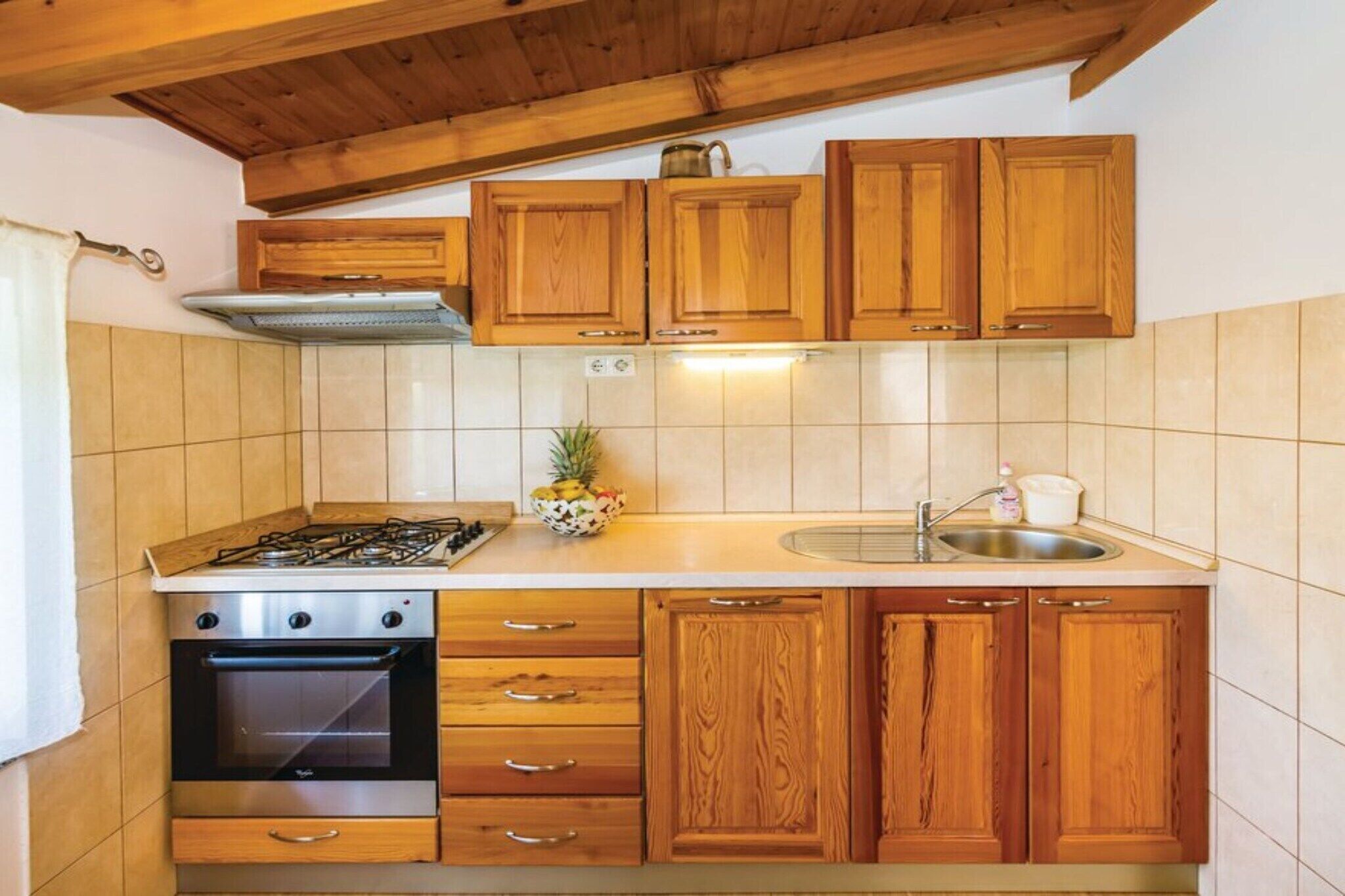 A kitchen with wooden cabinets, a gas stove, an oven, and a sink.