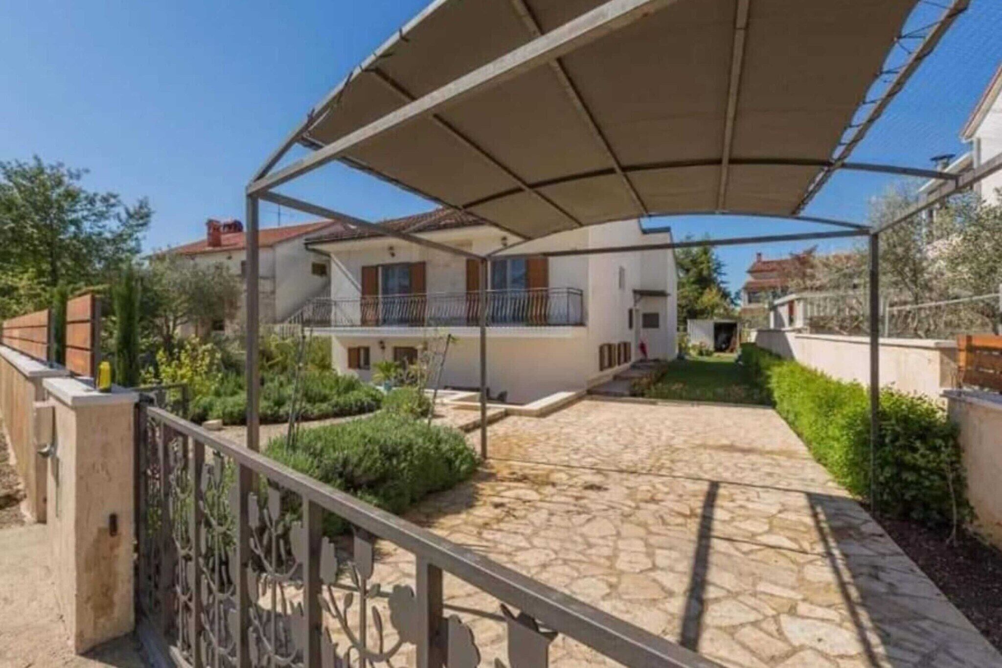 A covered outdoor area with a stone pathway leading to a building with a balcony.