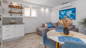 Un espacio habitable compacto con kitchenette, zona de comedor y sala de estar con sofá y sillones.