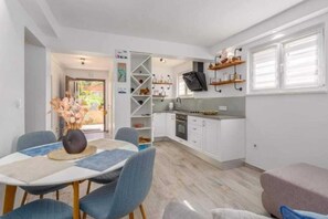 A compact kitchen with white cabinets, a built-in oven, and a TV mounted on the wall. - Two Bedroom Apartment with Terrace (Pula)