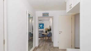 Un pasillo con un comedor, un cartel que dice "BEACH TIME" y una puerta que da a otra habitación.