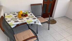 A small outdoor dining area with a table set for two, featuring a floral tablecloth and a fruit platter. - Apartments Fortuna - Studio Apartment with Balcony (Biograd na Moru)