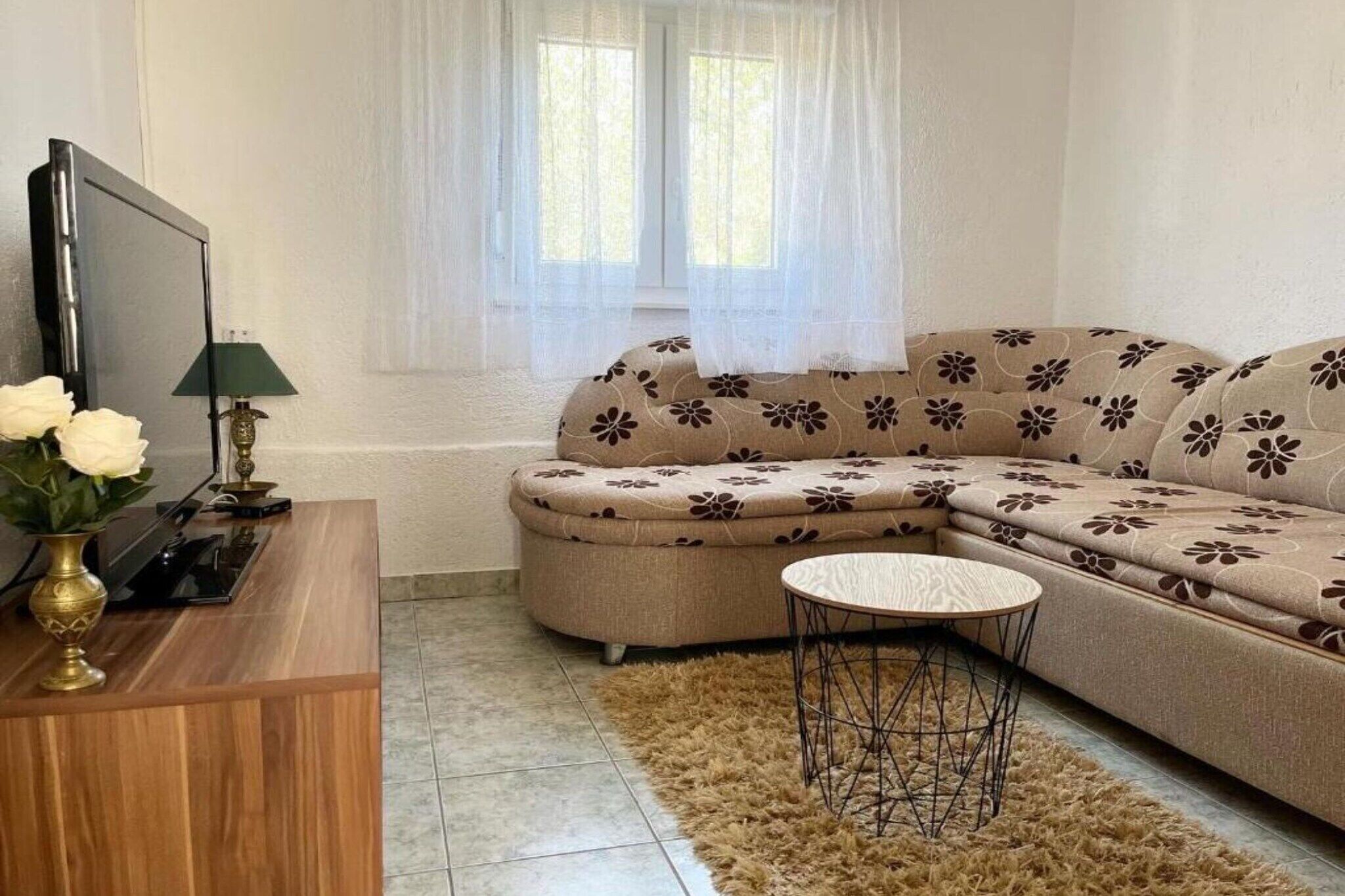 Un saló amb un sofà, una televisió, una taula petita i un vas decoratiu.