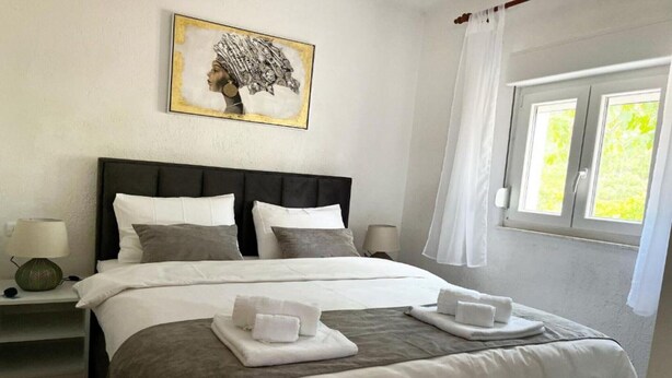 A neatly made bed with white and gray bedding, a bedside lamp, and a framed artwork on the wall. - One Bedroom Apartment with Balcony (3) (Biograd na Moru)