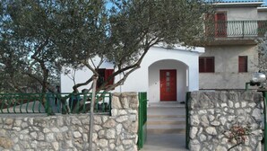 A stone-walled building with a red door and a green gate, suggesting a traditional architectural style. - One Bedroom apartment with Terrace (Šibenik)
