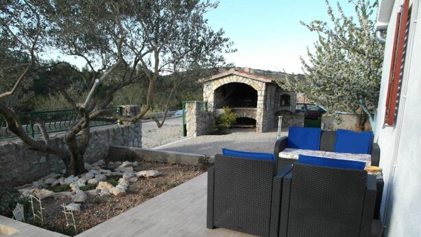 An outdoor seating area with a stone-built barbecue and a stone wall. - One Bedroom apartment with Terrace (Šibenik)
