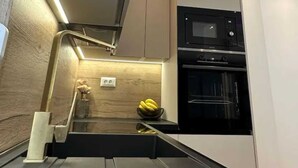 Een moderne keuken met een inbouwmagnetron, oven en een houten spatwand.