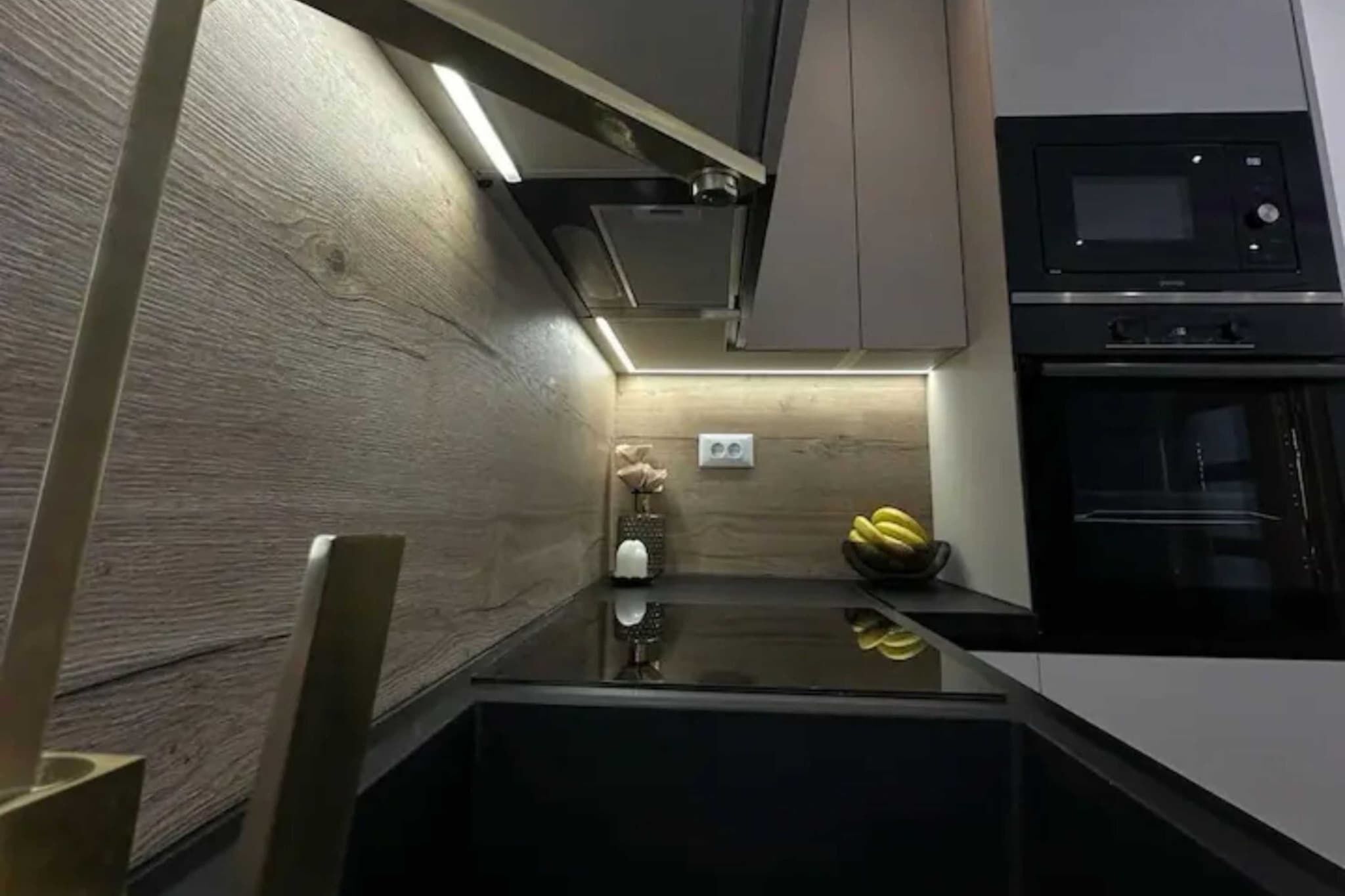 Eine moderne Küche mit schwarzem Arbeitsplatz, einer Mikrowelle und einem eingebauten Backofen.