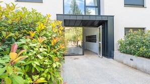 Une entrée moderne, avec un passage couvert menant à une porte en verre.