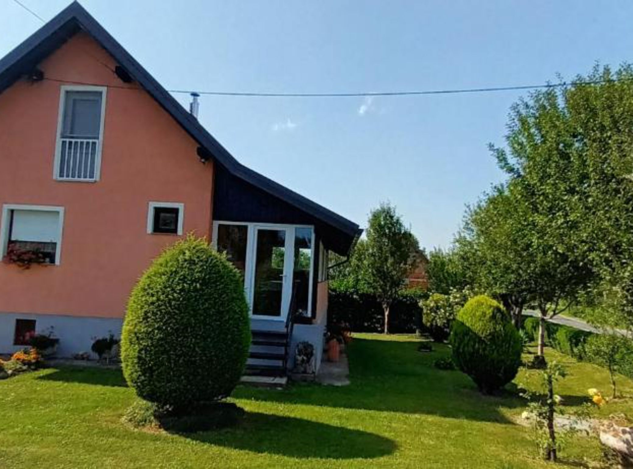 Een huis met een schuin dak, een veranda en een verzorgd gazon.