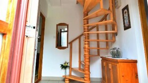 A wooden spiral staircase in a hallway with a mirror on the wall and a small plant. - Holiday Apartment Vuković (Saborsko)