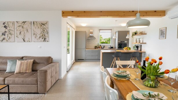 A modern kitchen with a dining area, featuring a wooden ceiling, grey cabinets, and a central island. - Holiday Home Milevoj - Three Bedroom Holiday Home (Labin)