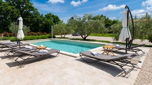 A poolside area with lounge chairs and umbrellas, surrounded by trees and a clear sky. - Holiday Home Milevoj - Three Bedroom Holiday Home (Labin)