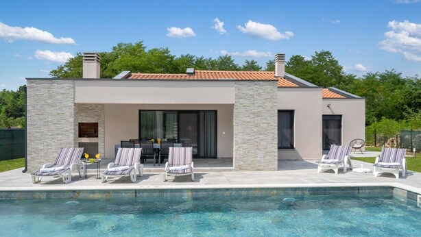Ein modernes Haus mit Swimmingpool, Sitzgelegenheiten im Freien und einer Terrasse.