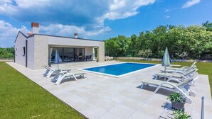 A modern house with a swimming pool, outdoor seating, and a well-maintained lawn. - Three Bedroom Villa with Swiming Pool (Rasa)