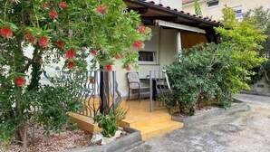 Il s’agit d’une propriété résidentielle dotée d’un patio couvert, d’un petit jardin agrémenté de plantes à fleurs rouges et d’une rambarde en métal.