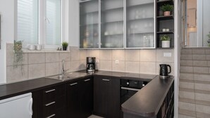 A modern kitchen with dark cabinetry, a built-in dishwasher, and a coffee maker. - Holiday Home Lea - Three Bedroom Holiday Home with Terrace and Sea View (Maslinica)