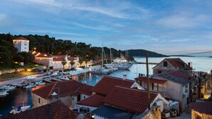 A coastal town with a marina, stone buildings with red-tiled roofs, and a tower-like structure. - Holiday Home Lea - Three Bedroom Holiday Home with Terrace and Sea View (Maslinica)