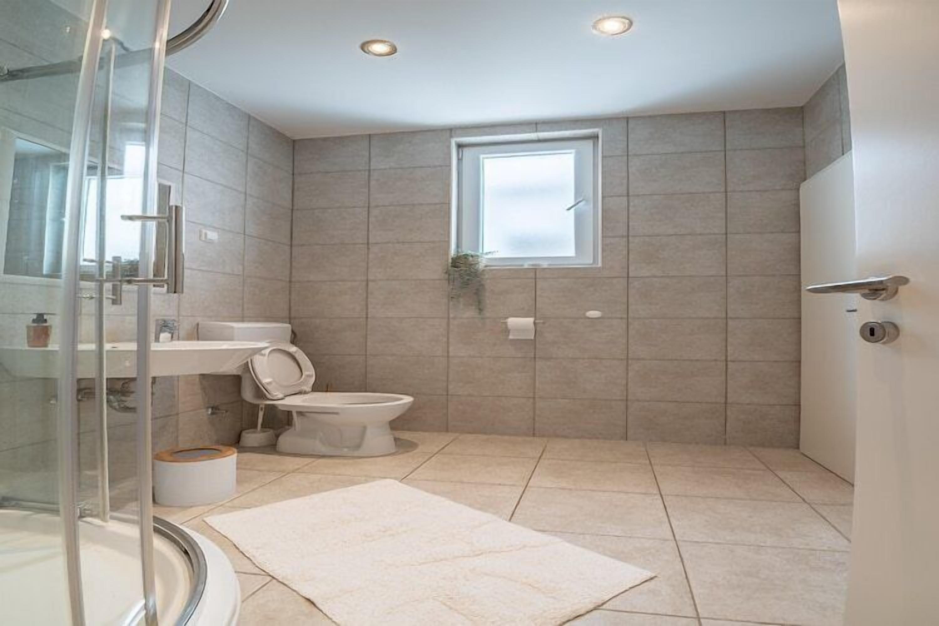 Un baño moderno con cabina de ducha de vidrio, inodoro y lavabo.