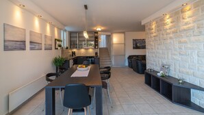 A modern kitchen with a dining area, featuring a long table, chairs, and a built-in bench along the wall. - Holiday Home Lea - Three Bedroom Holiday Home with Terrace and Sea View (Maslinica)