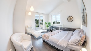 A modern bedroom with a bed, a chair, a desk, and large windows. - Holiday Home Lea - Three Bedroom Holiday Home with Terrace and Sea View (Maslinica)