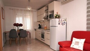 Un espacio habitable compacto con comedor, kitchenette y un sofá rojo.