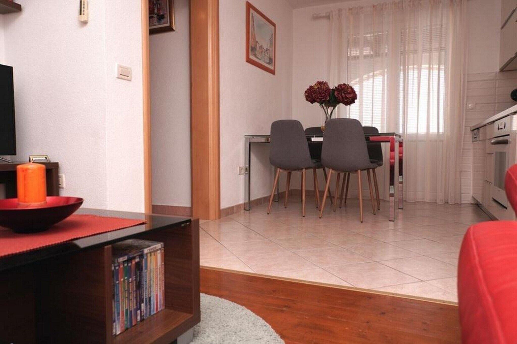 Un espacio habitable compacto con comedor, televisor y estantería.