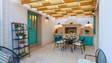 Un patio acogedor con mesa y sillas, una chimenea y una puerta verde.