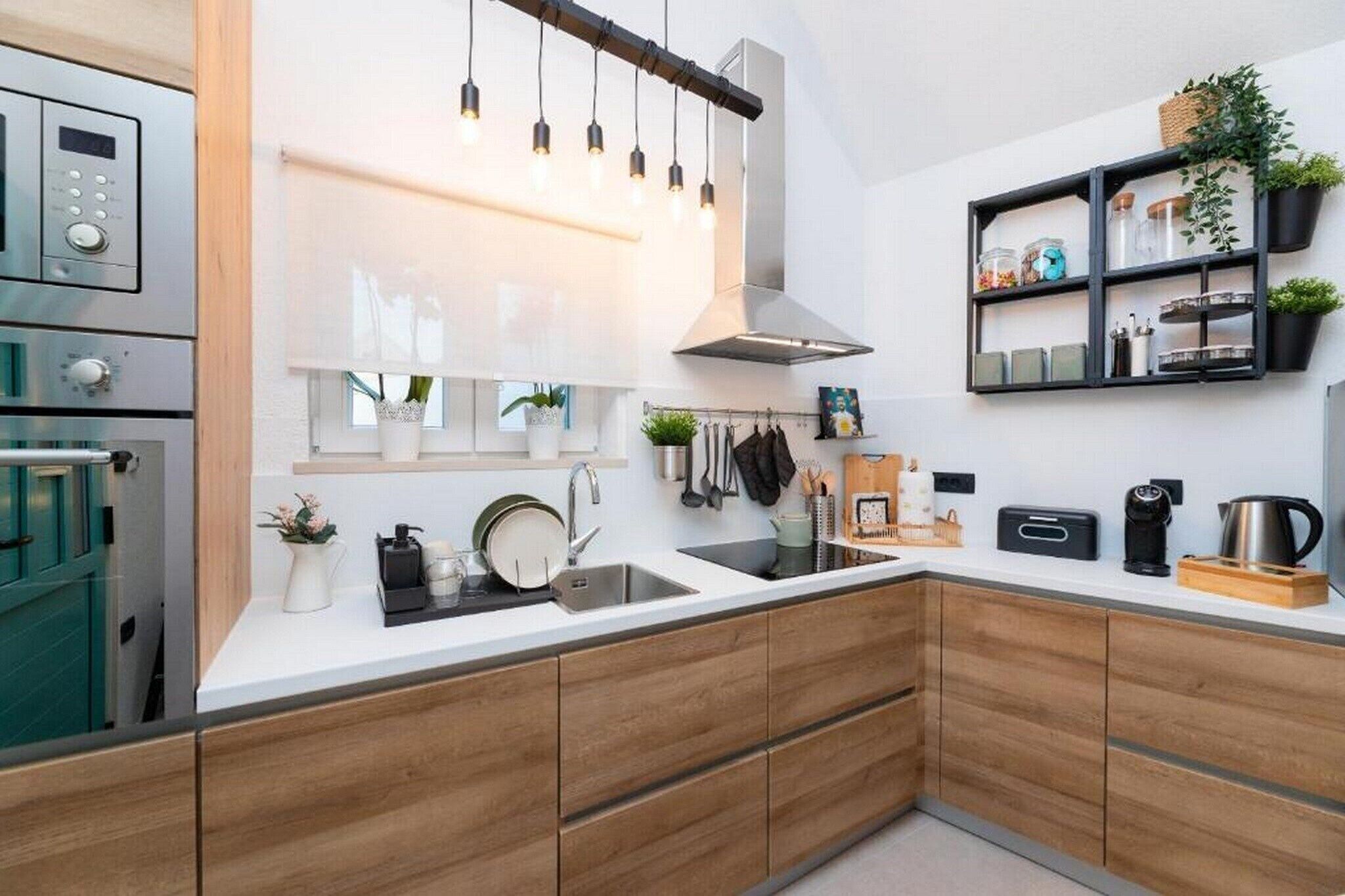 Una cocina moderna con armarios de madera, un lavamanos de acero inoxidable y un horno empotrado.