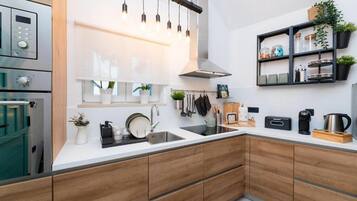 Una cocina moderna con armarios de madera, un lavamanos de acero inoxidable y un horno empotrado.