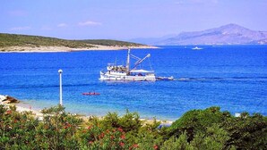 A boat anchored in a clear blue sea with a mountainous backdrop. - Apartments Gracin - One Bedroom Apartment with Terrace (A1) (Povlja)