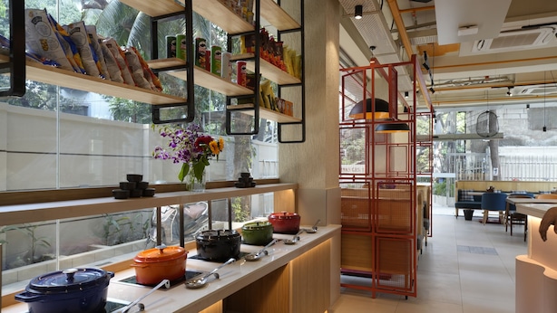 A modern kitchen with wooden shelves, cooking pots, and a red rack.