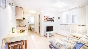 A compact living space with a kitchenette, a dining area, a TV, and a bed.