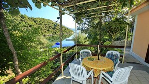 Un patio al aire libre con una mesa y sillas, con vista a un paisaje pintoresco de un lago y colinas.