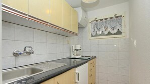 Una cocina con lavamanos, cafetera y armarios.