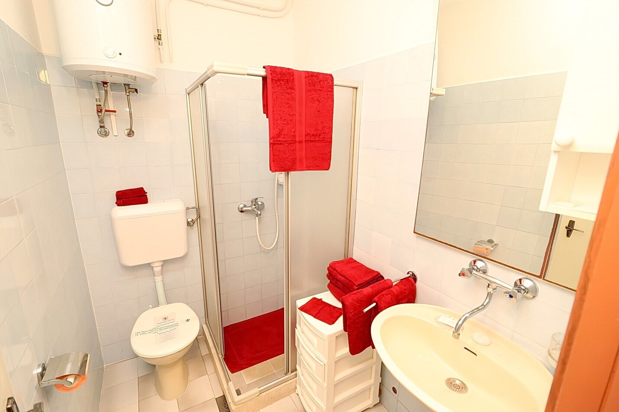 A bathroom with a glass-enclosed shower, a toilet, and a sink.
