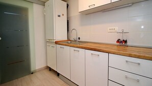 Una cocina moderna con armarios blancos, encimera de madera y pileta de acero inoxidable.