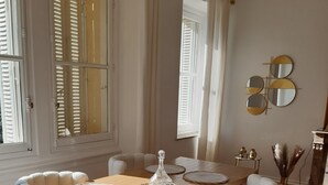 En matplats med ett träbord, vita stolar med vaddering och en dekorativ vas.