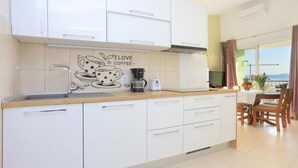 A modern kitchen with white cabinets, a coffee-themed backsplash, and a dining area with a table and chairs.