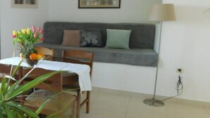 A cozy living room with a sofa, a dining table with chairs, and a lamp.