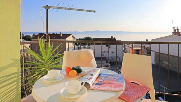 A balcony with a table set for tea, a magazine, and a plant.