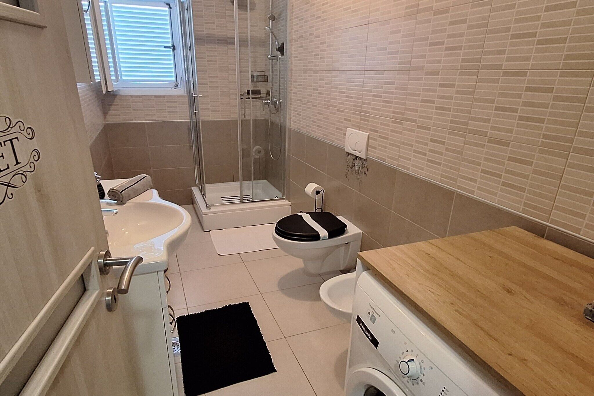 Une petite salle de bain comprenant une douche, des toilettes, un lavabo et un lave-linge.