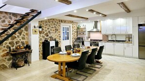 A spacious kitchen with white cabinets, a dining area with a wooden table, and a stone wall. - Villa Nika - Three Bedroom Villa with Private Pool (Lozovac)