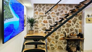A staircase with a stone wall, a wooden table with a basket, and a large painting on the wall. - Villa Nika - Three Bedroom Villa with Private Pool (Lozovac)