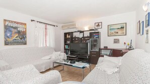 Een woonkamer met een bank, een salontafel, een televisie en een boekenkast.